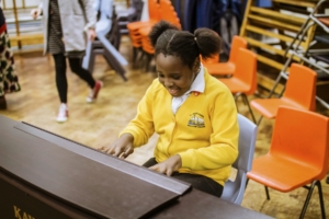 Little girl smiling whilst playing piano