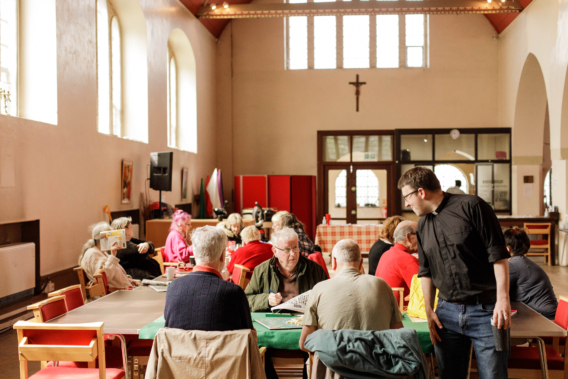 The interior of the Downham Estate church, filled with people interacting at tables 